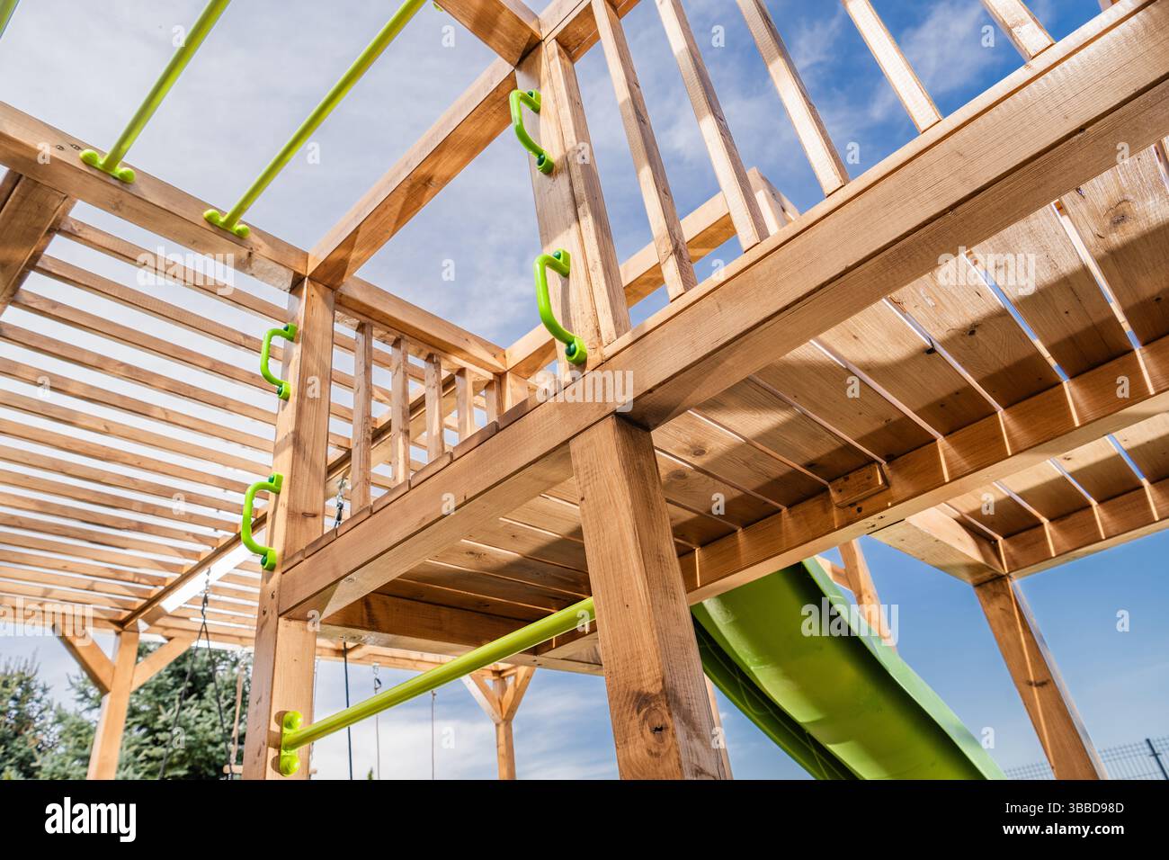 Cette structure de jeu extérieure présente des poutres en bois robustes et des éléments d'escalade verts vibrants. Il offre un toboggan et diverses caractéristiques d'escalade, perfec Banque D'Images