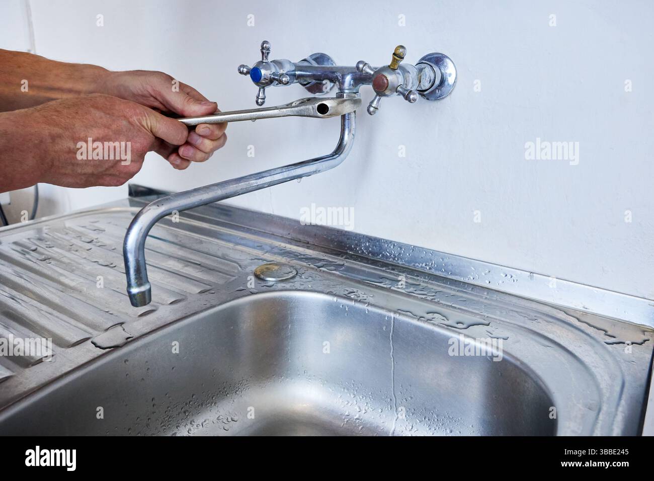 L'installation du bec verseur incurvé sur le robinet mural se fait à l'aide d'une clé réglable généralement utilisée pour serrer ou desserrer les écrous et les boulons, Water dr. Banque D'Images