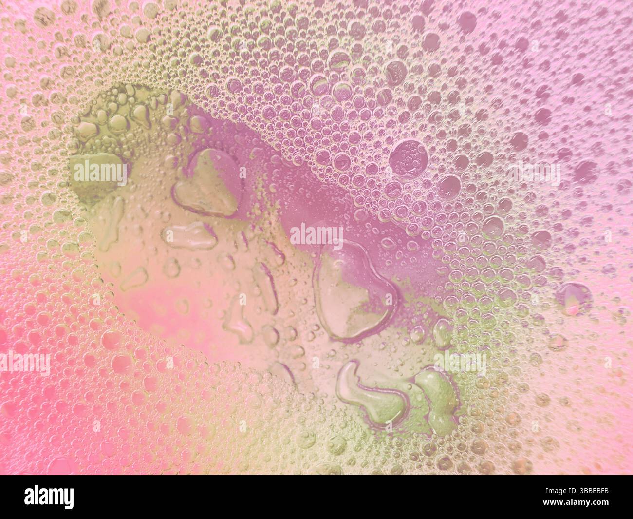 Empreinte de coeur dans des bulles de mousse savonneuse laisse une traînée d'empreintes dans un motif abstrait montrant l'amour et le soin sur la surface rose humide de couleur pastel violet. Banque D'Images