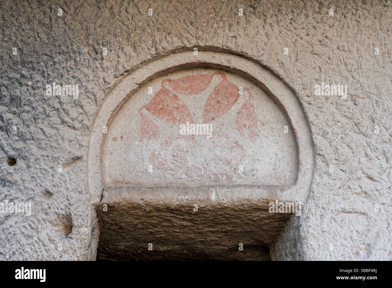 Une simple arche en pierre est sculptée dans le mur de l'église sombre de Goreme, reflétant le style architectural byzantin minimaliste. Banque D'Images
