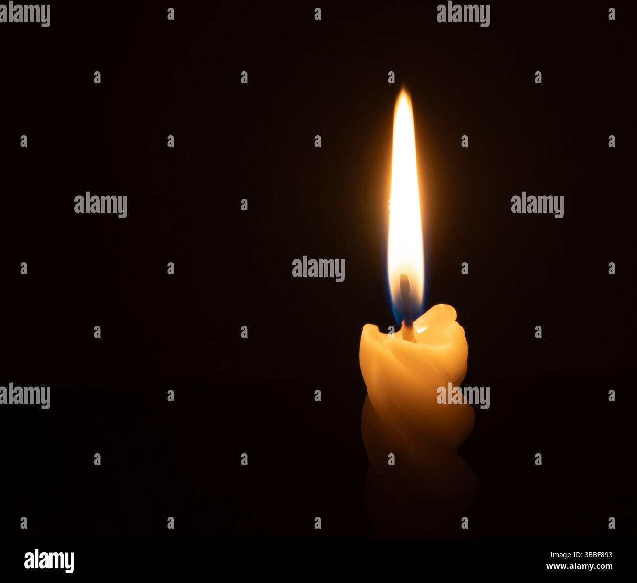 Une flamme ou une lumière de bougie allumée unique brille sur une bougie blanche spirale sur fond noir ou sombre sur la table dans l'église pour Noël, funérailles ou moi Banque D'Images