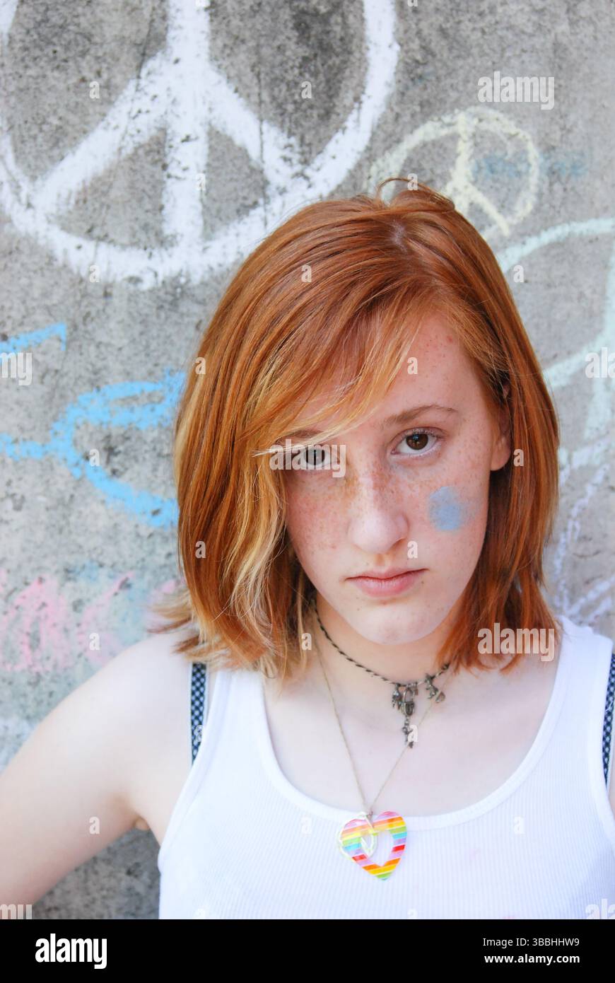 Jeune femme avec de la craie sur la joue qui a l'air sérieuse Banque D'Images