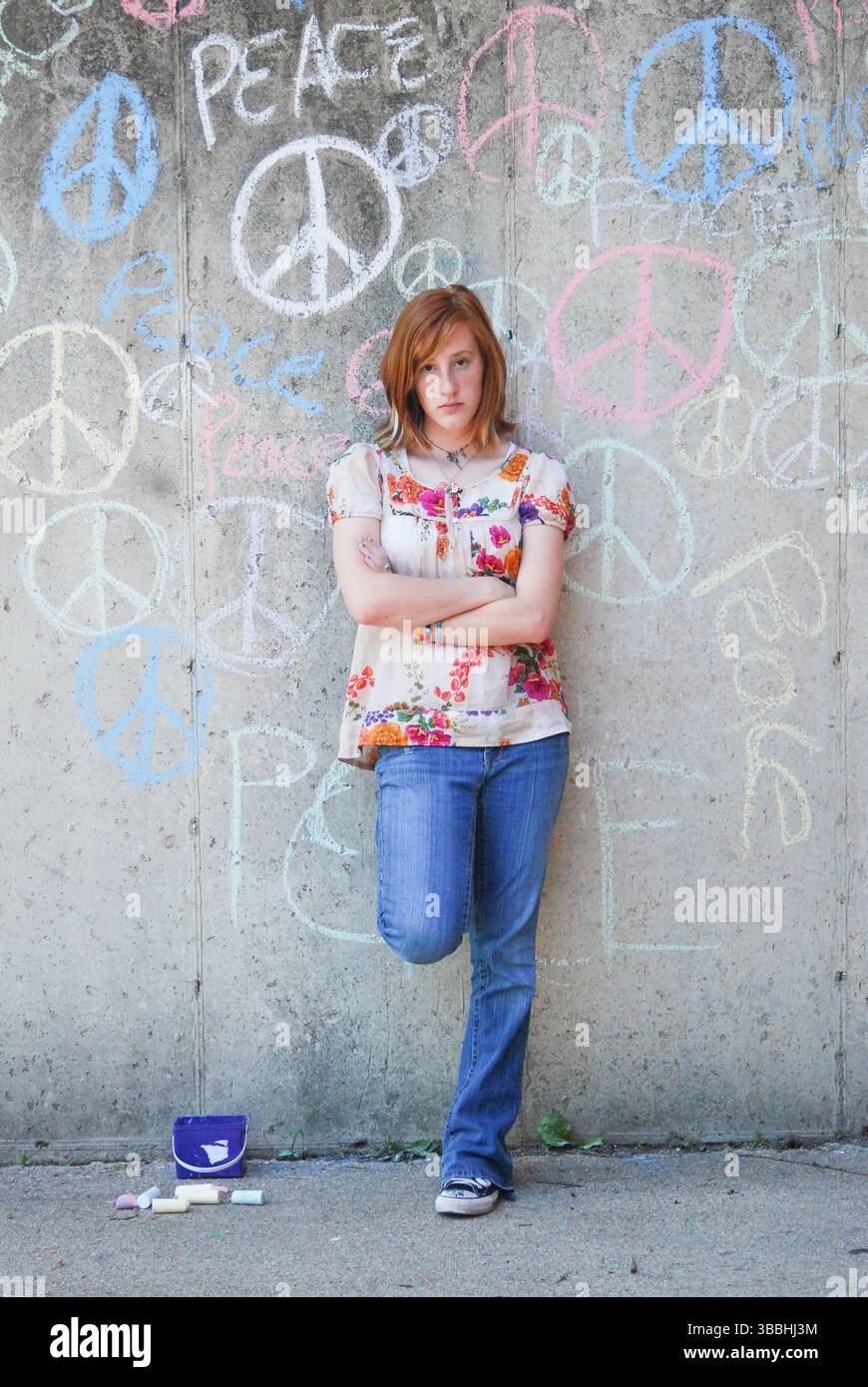 Jeune femme avec attitude se penche contre Graffiti Covered Wall Banque D'Images