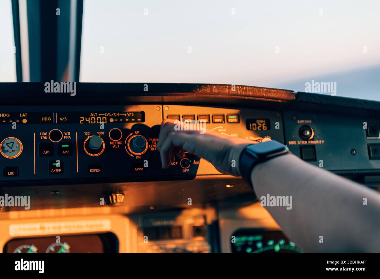Pilote ajustant les commandes du pilote automatique dans le poste de pilotage de l'avion pendant le coucher du soleil Banque D'Images