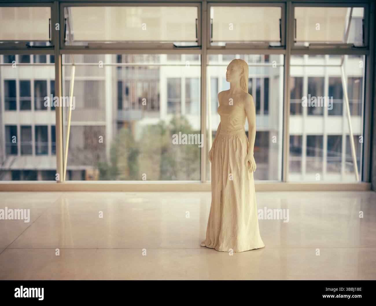 Sculpture féminine en céramique contemporaine dans la galerie minimaliste avec fond de fenêtre urbaine Banque D'Images