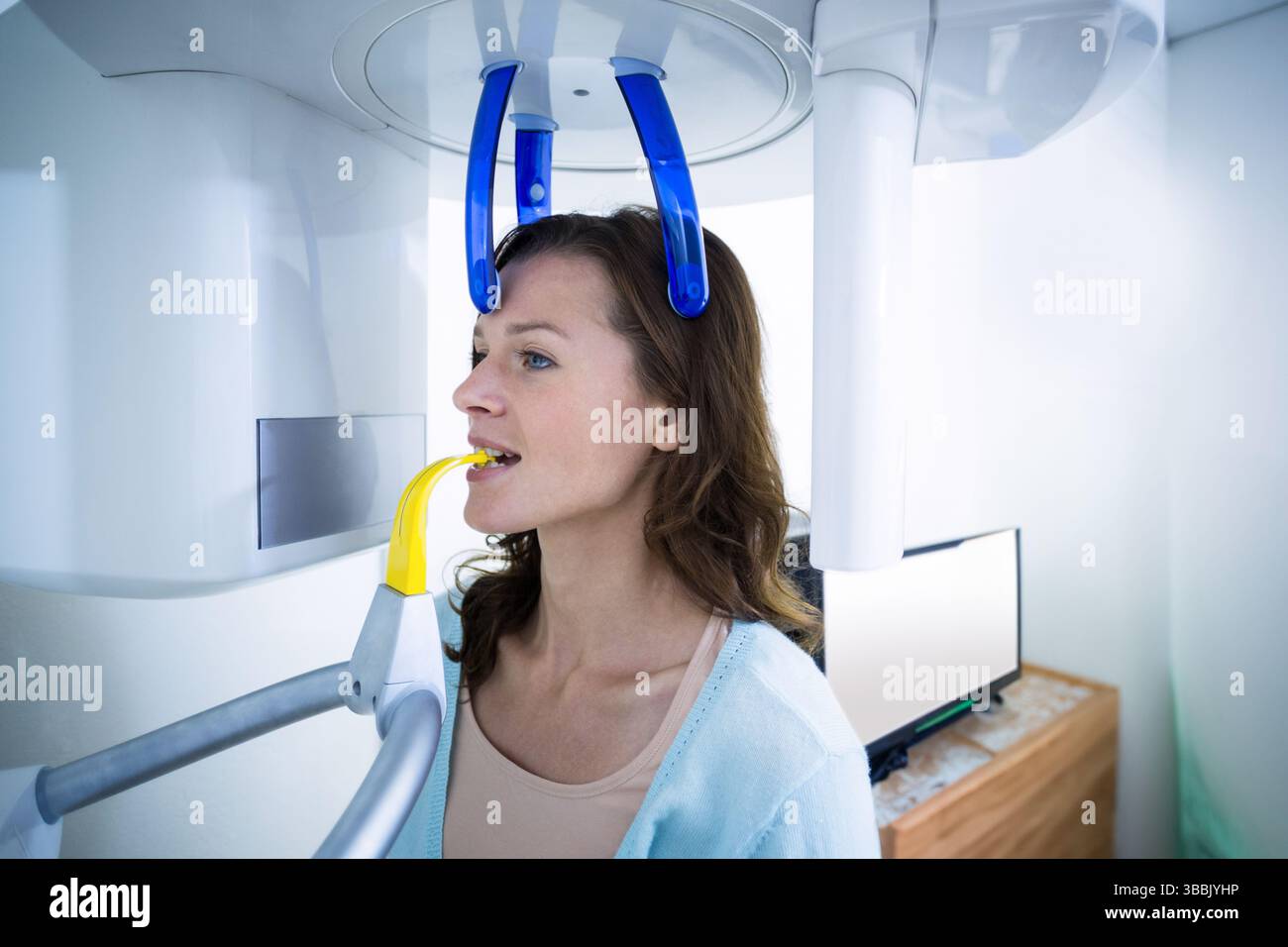 Appareil de radiographie dentaire panoramique montrant le patient mordant l'embout buccal jaune dans une salle clinique propre Banque D'Images