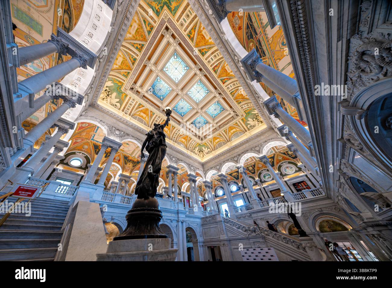 WASHINGTON DC — le Grand Hall du Thomas Jefferson Building à la Bibliothèque du Congrès présente un escalier monumental en marbre flanqué de figures féminines en bronze avec des bras dressés tenant des électroliers en forme de torche. Créées par le sculpteur Philip Martiny dans les années 1890, ces statues allégoriques servent à la fois d'éléments décoratifs et de luminaires fonctionnels dans l'intérieur orné des Beaux-Arts. Le Grand Hall, achevé en 1897, présente des colonnes de marbre élaborées, des ornements dorés, des sols en mosaïque et un plafond à caissons orné de puits de lumière plaqués cuivre, illustrant la Renaissance américaine Banque D'Images