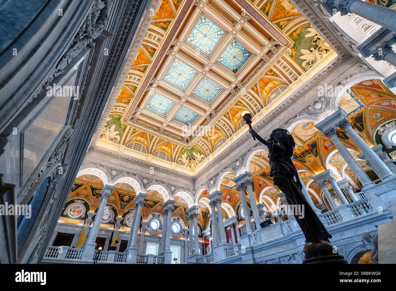WASHINGTON DC — le Grand Hall du Thomas Jefferson Building à la Bibliothèque du Congrès présente un escalier monumental en marbre flanqué de figures féminines en bronze avec des bras dressés tenant des électroliers en forme de torche. Créées par le sculpteur Philip Martiny dans les années 1890, ces statues allégoriques servent à la fois d'éléments décoratifs et de luminaires fonctionnels dans l'intérieur orné des Beaux-Arts. Le Grand Hall, achevé en 1897, présente des colonnes de marbre élaborées, des ornements dorés, des sols en mosaïque et un plafond à caissons orné de puits de lumière plaqués cuivre, illustrant la Renaissance américaine Banque D'Images