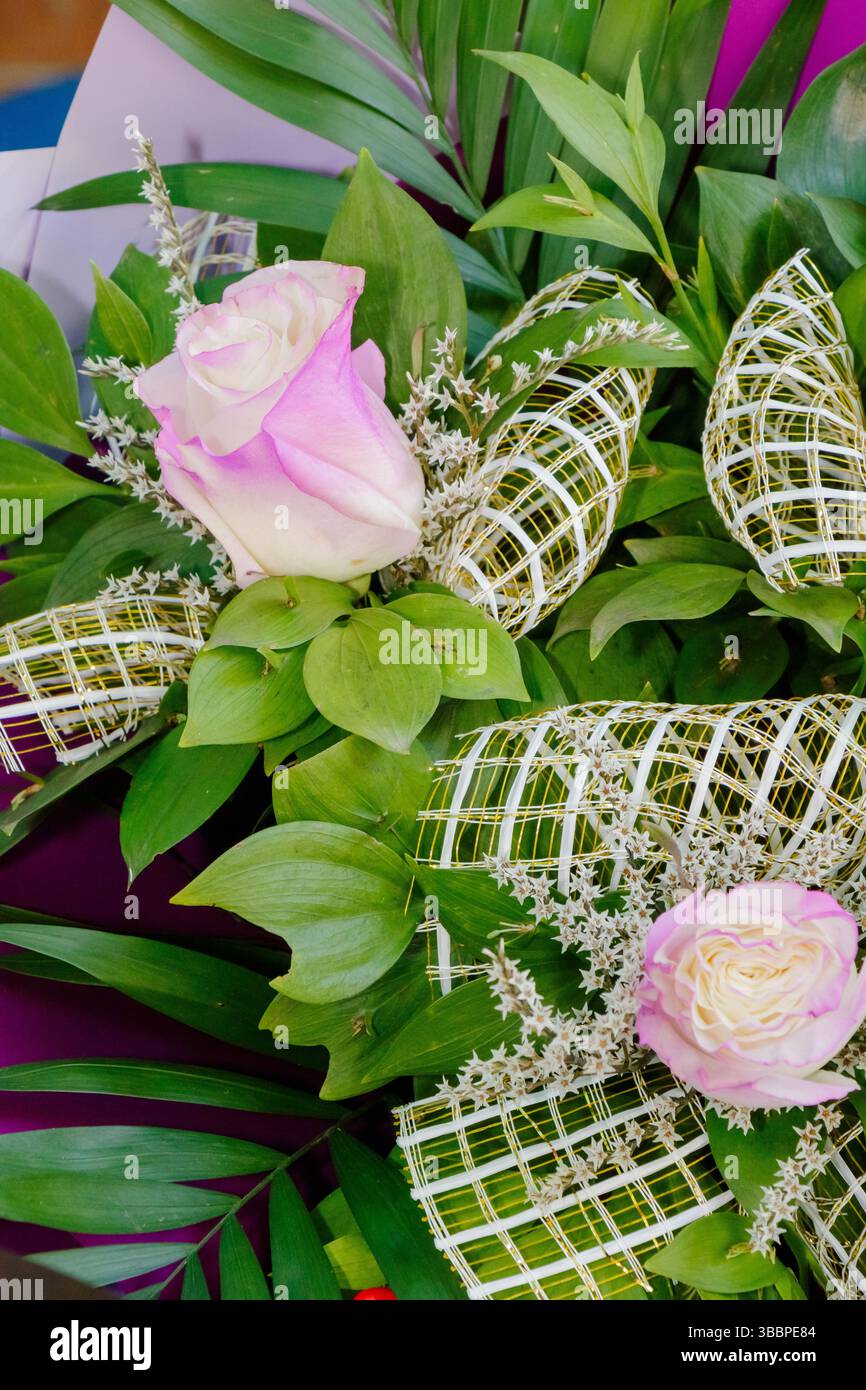 Un magnifique arrangement de roses roses est mis en valeur parmi la verdure vibrante et les décorations complexes. L'affichage floral apporte une touche d'élégance à t Banque D'Images