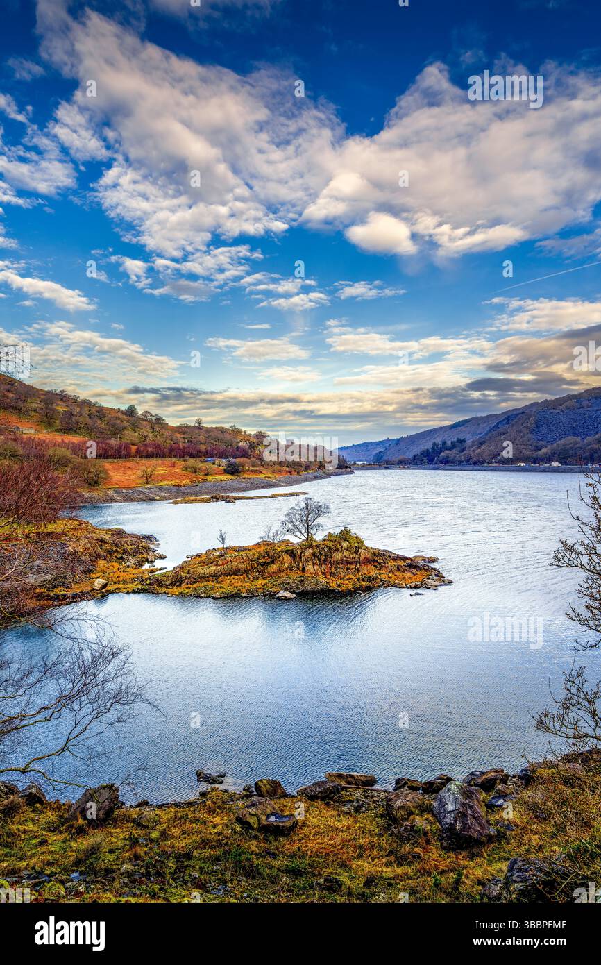tarn glaciaire bordé de chênes balayés par le vent et de rivages rocheux au pied du mont Snowdon sous un paysage nuageux mouvant Banque D'Images
