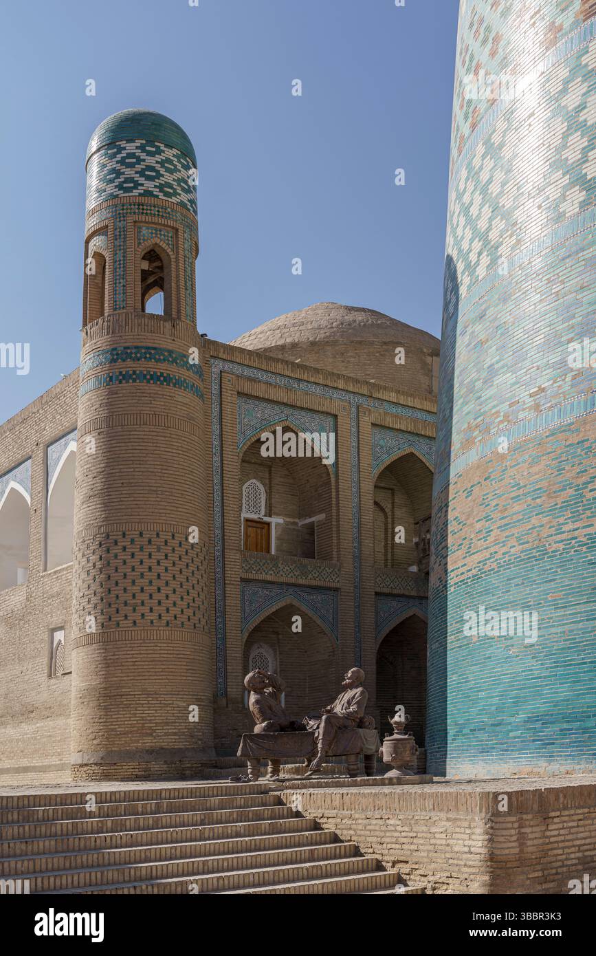 Un dôme turquoise et une entrée voûtée marquent la Madrasah Muhammad Aminkhan à Khiva Ouzbékistan avec des cornières décoratives et des murs de sable. Banque D'Images