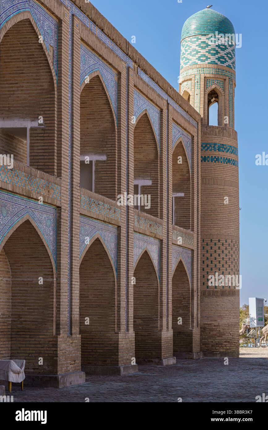 Une façade de deux étages avec des dômes turquoise et des fenêtres cintrées marque la Madrasah Muhammad Aminkhan à Khiva Ouzbékistan sous un ciel bleu clair. Banque D'Images
