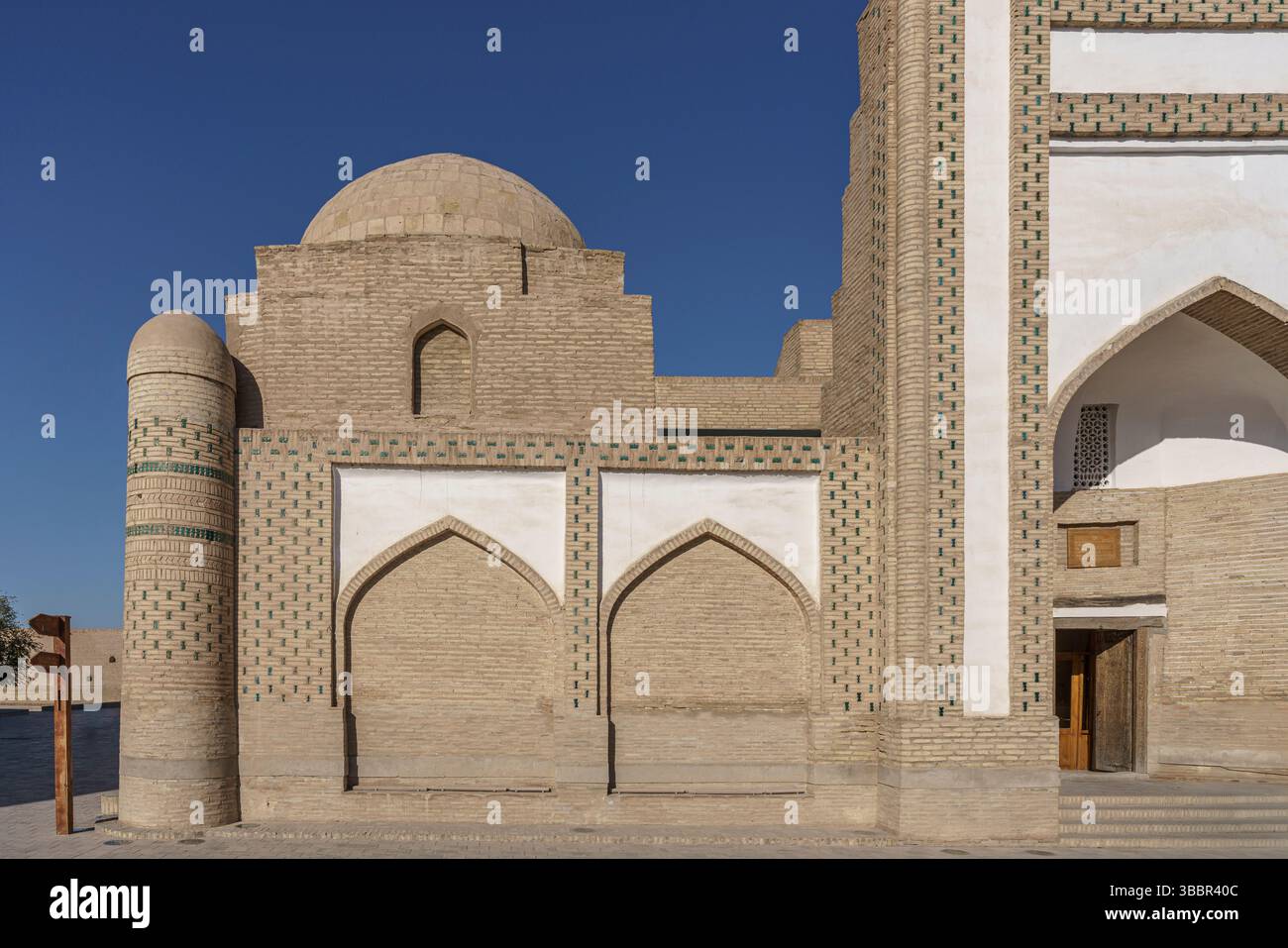 Un grand toit en forme de dôme avec des bandes de tuiles blanches et vertes couronne Muhammad Amin Inaq Madrasah à Khiva Ouzbékistan avec des entrées cintrées ci-dessous. Banque D'Images