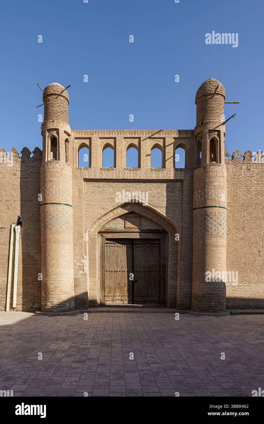Une porte fortifiée avec des tours jumelles et une entrée voûtée marque le mur historique de la ville de Khiva Ouzbékistan sous un ciel bleu sans nuages. Banque D'Images
