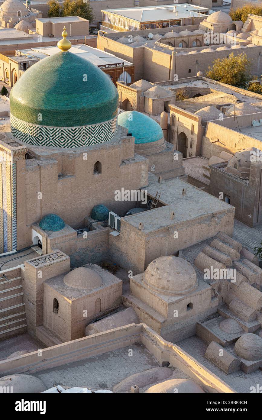 Le dôme vert et les murs de sable du mausolée de Pahlavan Mahmud se distinguent dans le vieux paysage urbain de Khiva Ouzbékistan au crépuscule. Banque D'Images