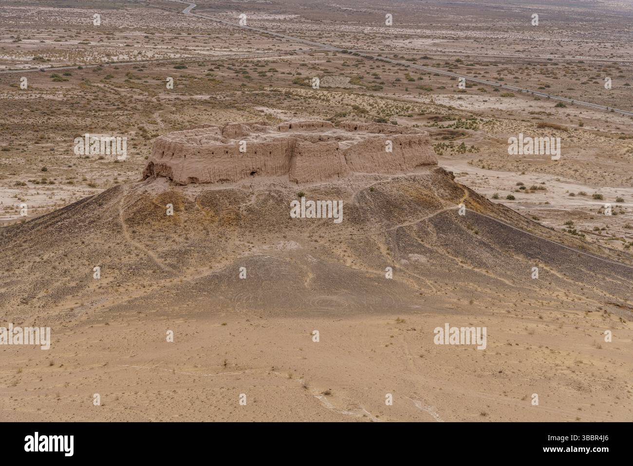 Les murs massifs et les tours de la forteresse Ayaz Kala s'élèvent au-dessus du désert environnant à Khorezm Ouzbékistan avec des dunes de sable en dessous. Banque D'Images