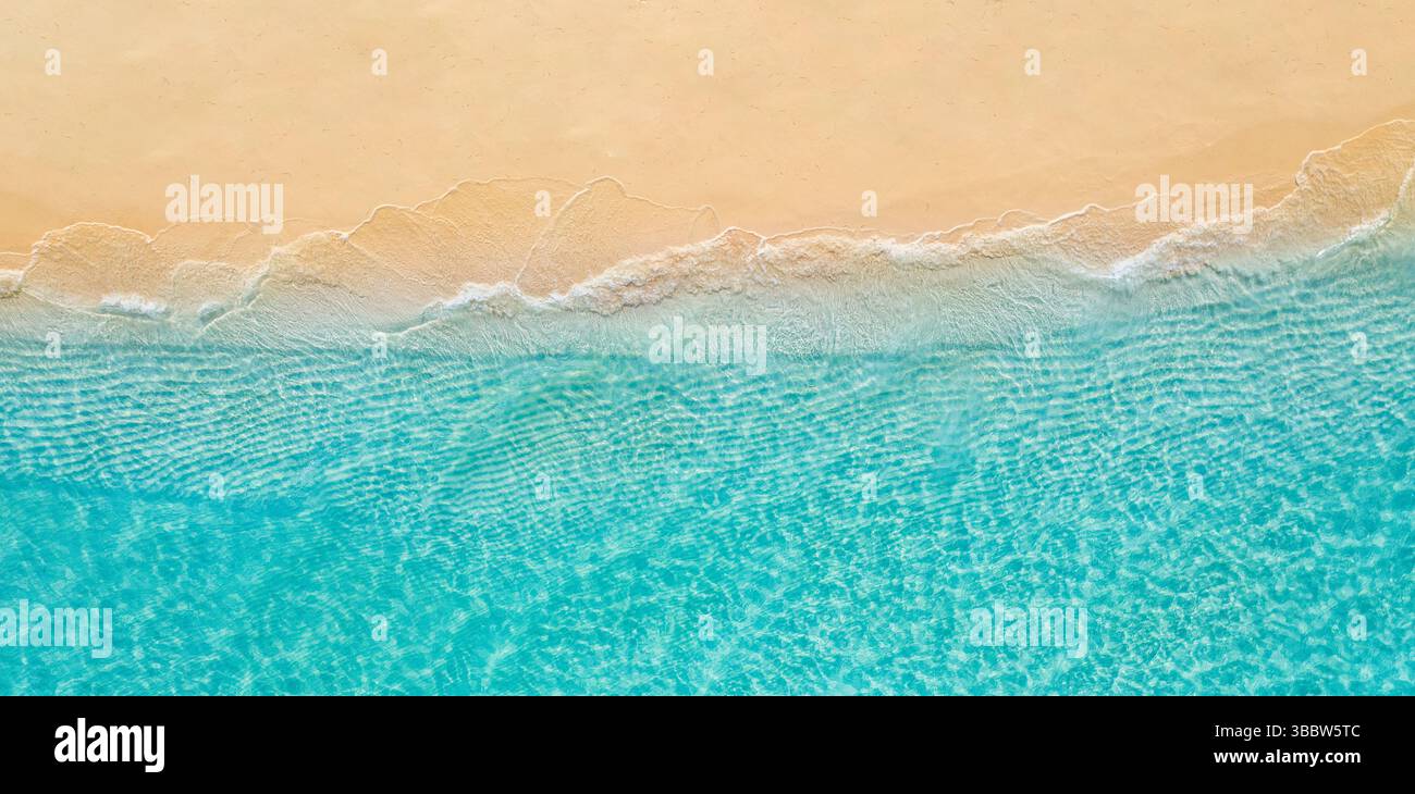 Paysage marin d'été belle vue aérienne en gros plan sur l'eau de mer bleue et les vagues éclaboussant la côte de plage de sable, fond de nature tropicale méditerranéenne ensoleillée Banque D'Images