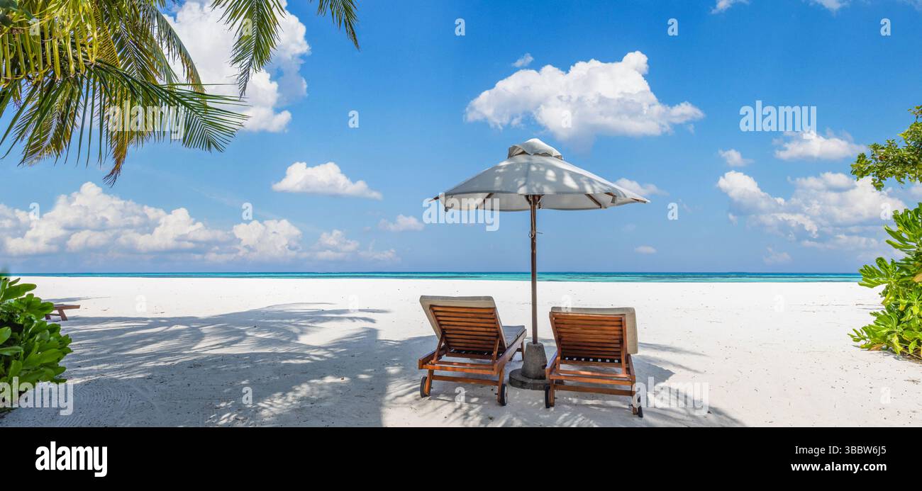 Belle plage panoramique avec des chaises ensoleillées sous parasol, couple romantique sur la destination de vacances île tropicale lune de miel, paysage d'été serein Banque D'Images