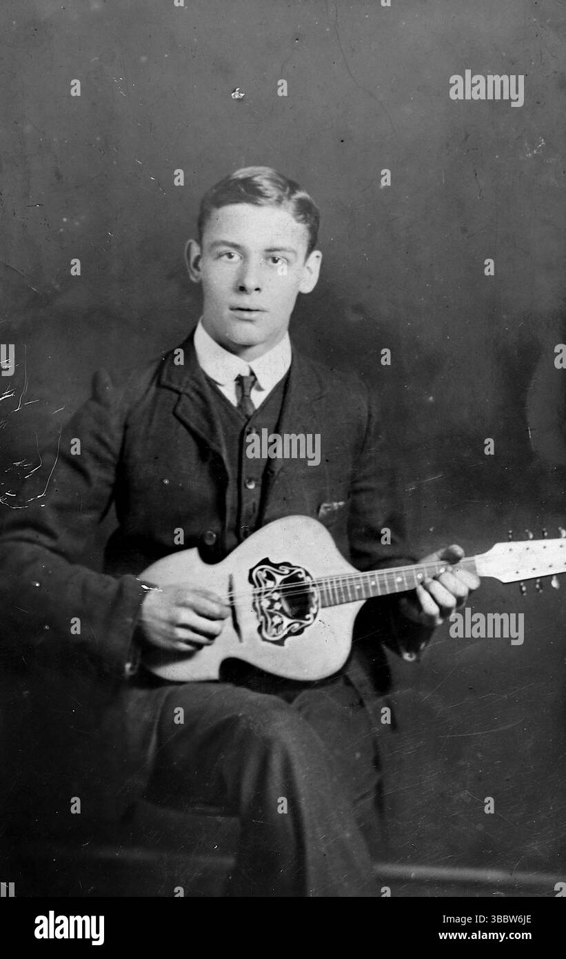 Histoire sociale, musique : un jeune homme, assis. Il est vêtu d'un costume et d'une cravate et joue une petite mandoline. Non attribué, vers 1905. D'une collection mixte de cartes postales édouardiennes. Banque D'Images