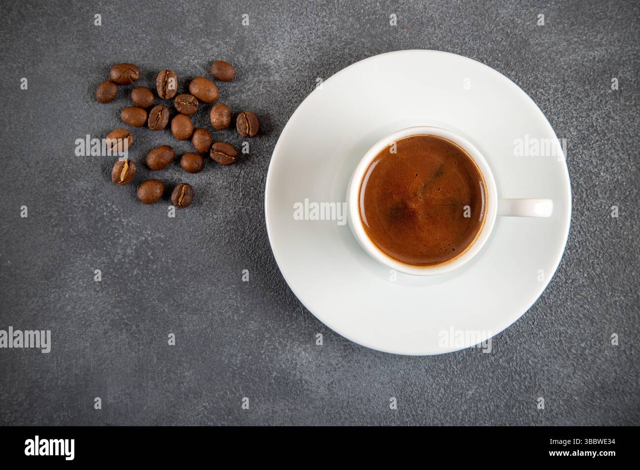 Grains de café torréfiés avec une tasse de café turc sur le fond de béton gris Banque D'Images