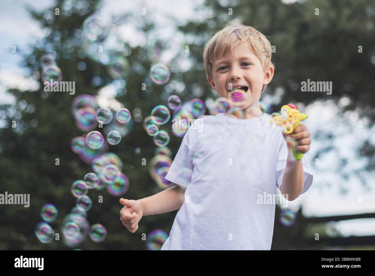un garçon de 5-6 ans joue avec des bulles de savon Banque D'Images
