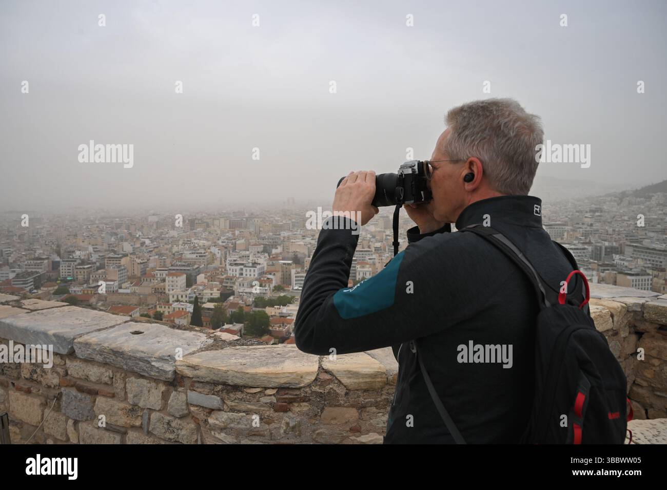 Athènes, Grèce, 16 mai 2025. Un visiteur prend des photos tandis qu'Athènes est vu couvert de nuages de poussière. Une épaisse couverture de poussière saharienne a balayé la capitale grecque vendredi, jetant de la brume sur la ville et suscitant des avertissements sanitaires de la part des autorités. Crédit : Dimitris Aspiotis/Alamy Live News Banque D'Images