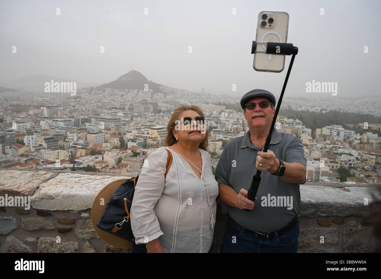 Athènes, Grèce, 16 mai 2025. Les visiteurs prennent des selfies tandis qu'Athènes est couverte de nuages de poussière. Une épaisse couverture de poussière saharienne a balayé la capitale grecque vendredi, jetant de la brume sur la ville et suscitant des avertissements sanitaires de la part des autorités. Crédit : Dimitris Aspiotis/Alamy Live News Banque D'Images