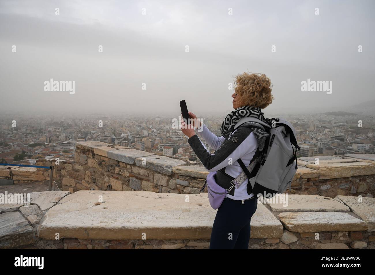 Athènes, Grèce, 16 mai 2025. Un visiteur prend des photos tandis qu'Athènes est vu couvert de nuages de poussière. Une épaisse couverture de poussière saharienne a balayé la capitale grecque vendredi, jetant de la brume sur la ville et suscitant des avertissements sanitaires de la part des autorités. Crédit : Dimitris Aspiotis/Alamy Live News Banque D'Images