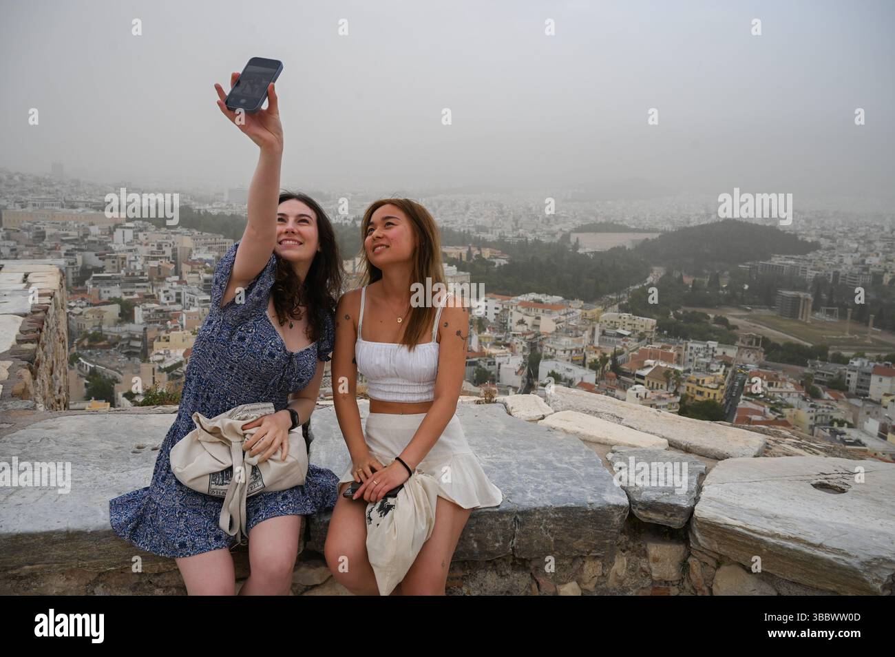 Athènes, Grèce, 16 mai 2025. Les visiteurs prennent des selfies tandis qu'Athènes est couverte de nuages de poussière. Une épaisse couverture de poussière saharienne a balayé la capitale grecque vendredi, jetant de la brume sur la ville et suscitant des avertissements sanitaires de la part des autorités. Crédit : Dimitris Aspiotis/Alamy Live News Banque D'Images