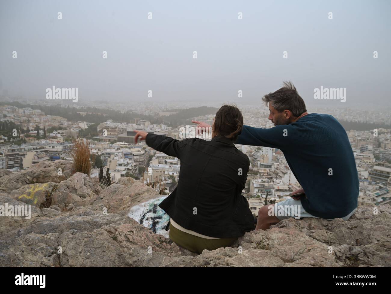 Athènes, Grèce, 16 mai 2025. Les visiteurs regardent au-dessus de la ville tandis qu'Athènes est couverte de nuages de poussière. Une épaisse couverture de poussière saharienne a balayé la capitale grecque vendredi, jetant de la brume sur la ville et suscitant des avertissements sanitaires de la part des autorités. Crédit : Dimitris Aspiotis/Alamy Live News Banque D'Images