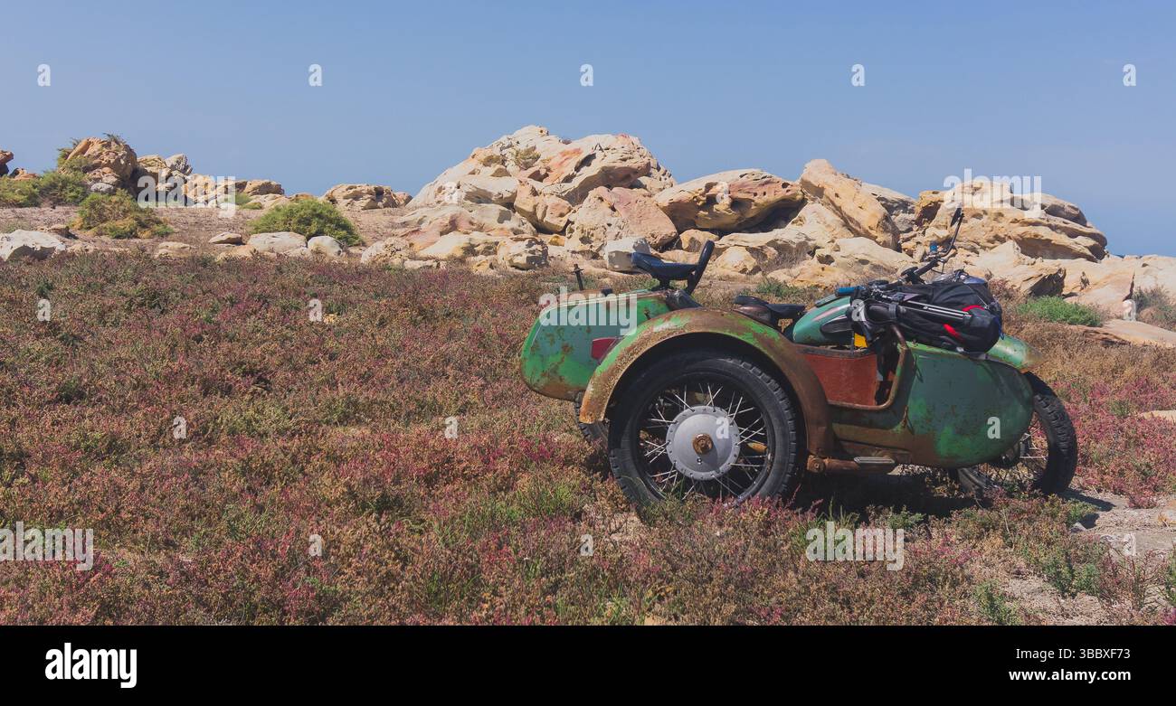 Moto de style ancien dans le domaine avec des fleurs et des rochers en arrière-plan dans l'île Banque D'Images
