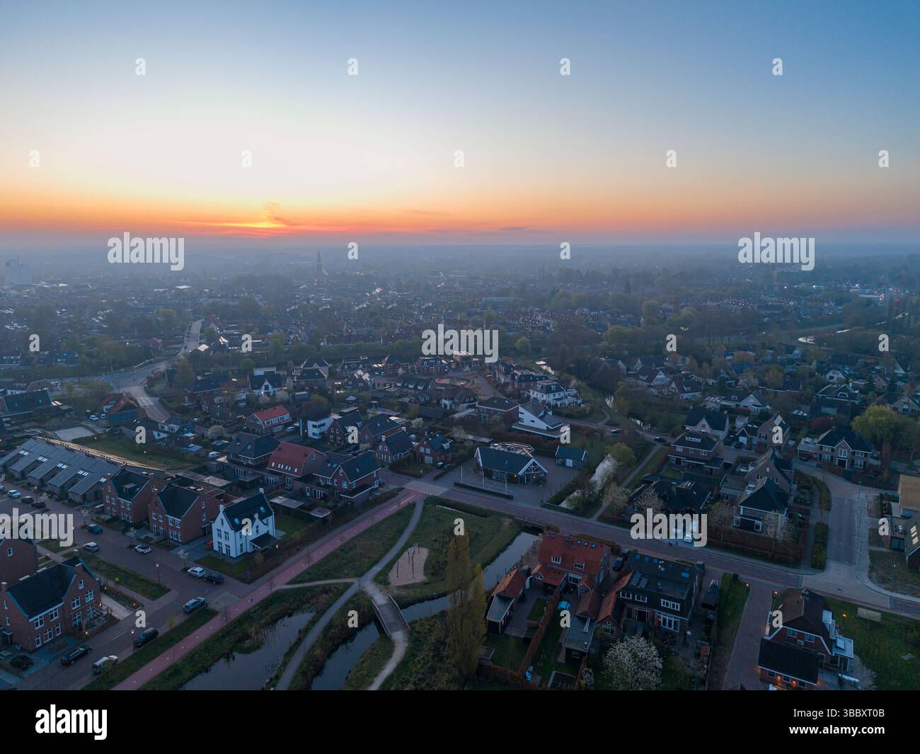 Une vue aérienne à couper le souffle de Nijkerk à l'aube, avec de charmantes maisons, des chemins sinueux, et une rivière tranquille tissant à travers le paysage. Banque D'Images