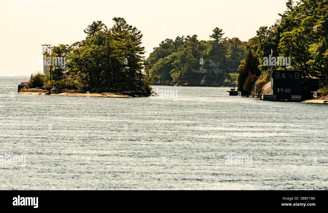 Île avec un phare et des chalets sur la rive éloignée d'une rivière Banque D'Images