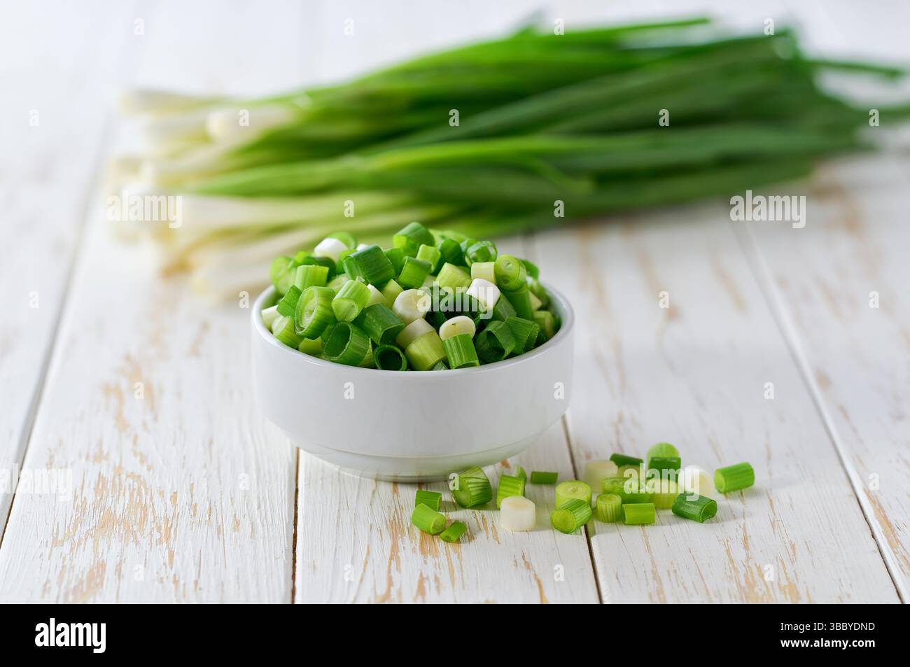 Des échalotes hachées ou de jeunes oignons de printemps dans un bol en céramique , sur une table de cuisine. Banque D'Images