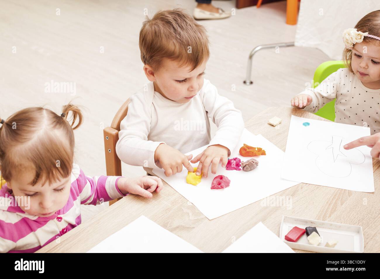 L'enseignant aide le jeune fille de faire une figure de la pâte à modeler sur la table Banque D'Images