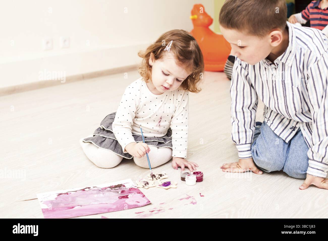 Fille, c'est peindre avec un pinceau et gouache sur papier sur le plancher Banque D'Images