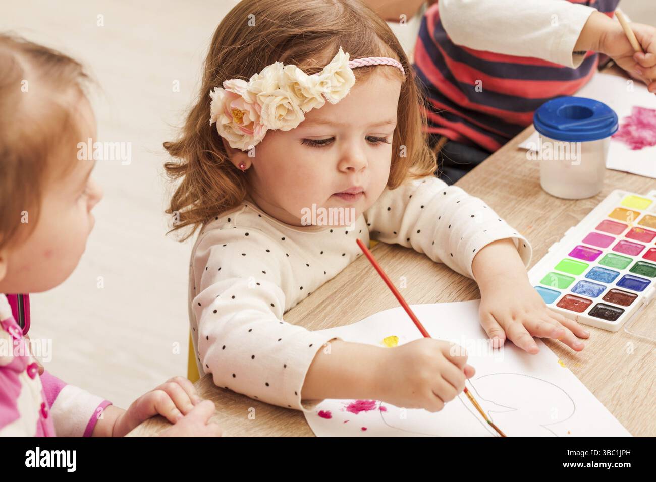 Les enfants de C02 ans apprennent à peindre avec un pinceau et des aquarelles sur papier dans la maternelle Banque D'Images
