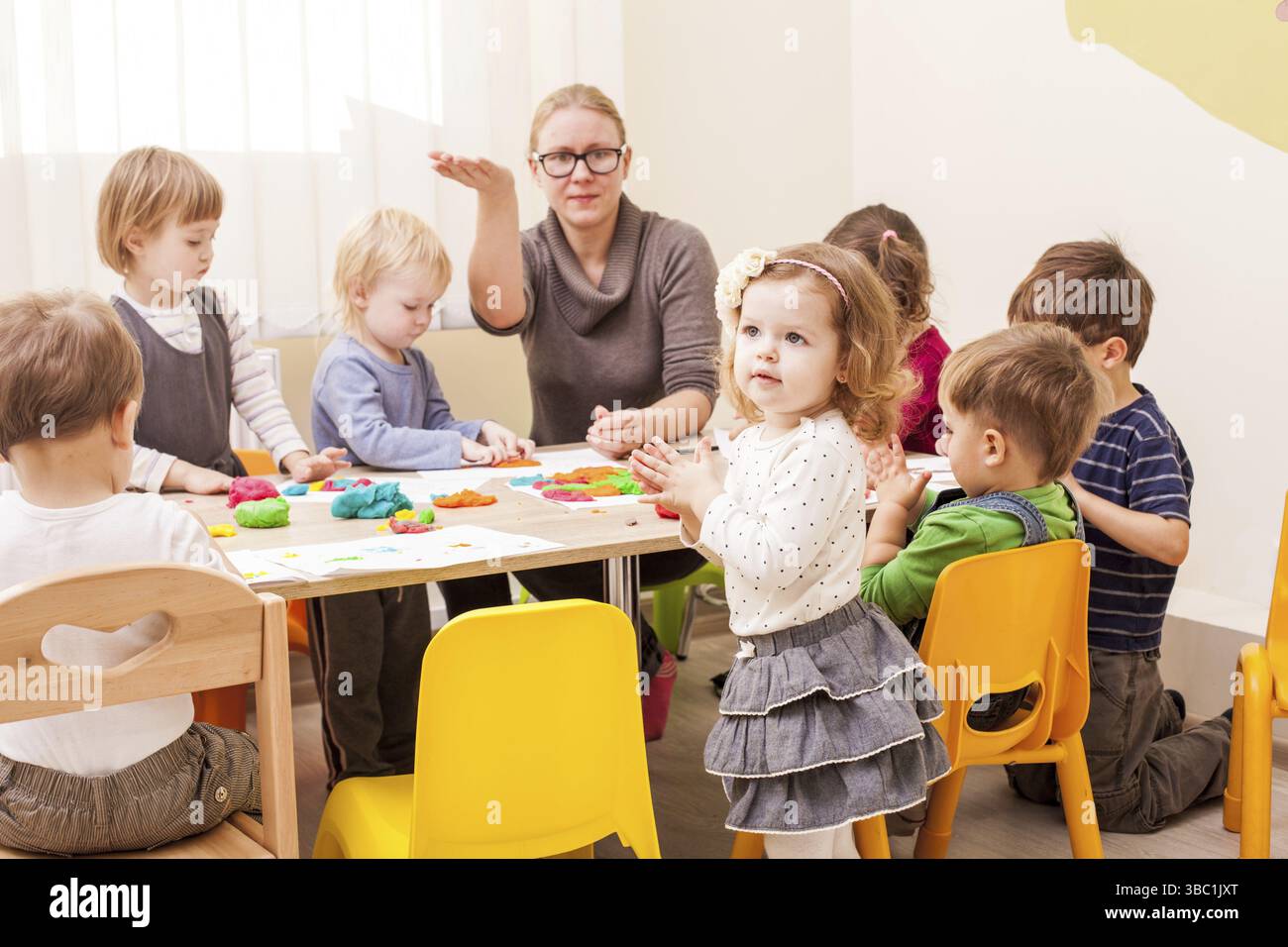 La fille fait une figure de plasticine près de la table Banque D'Images