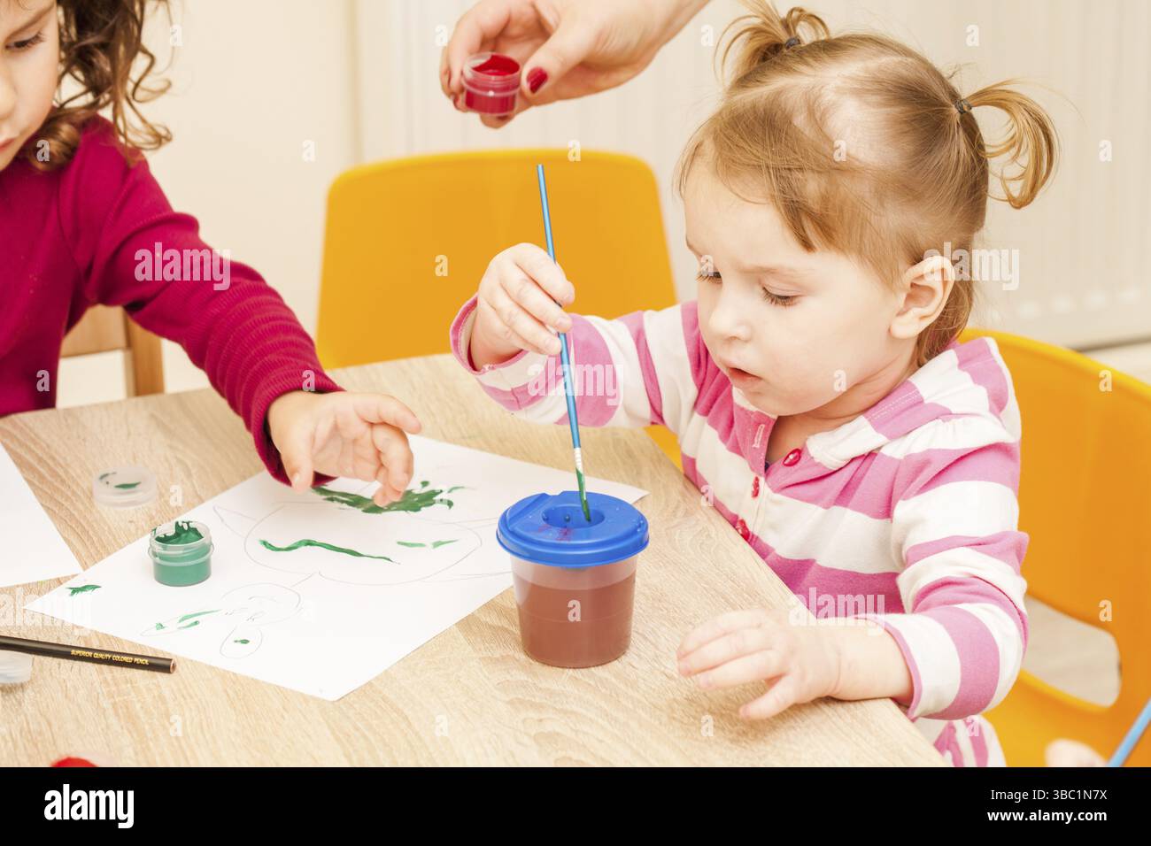 Fille, c'est peindre avec un pinceau et d'aquarelles sur papier dans le jardin d'enfants Banque D'Images