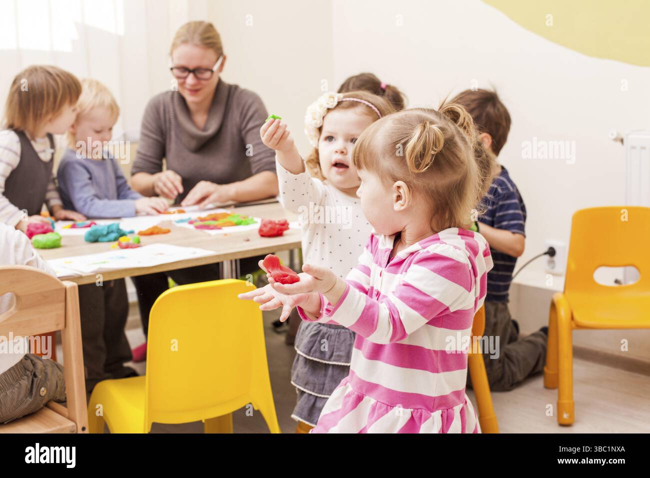 La fille fait une figure de plasticine près de la table Banque D'Images