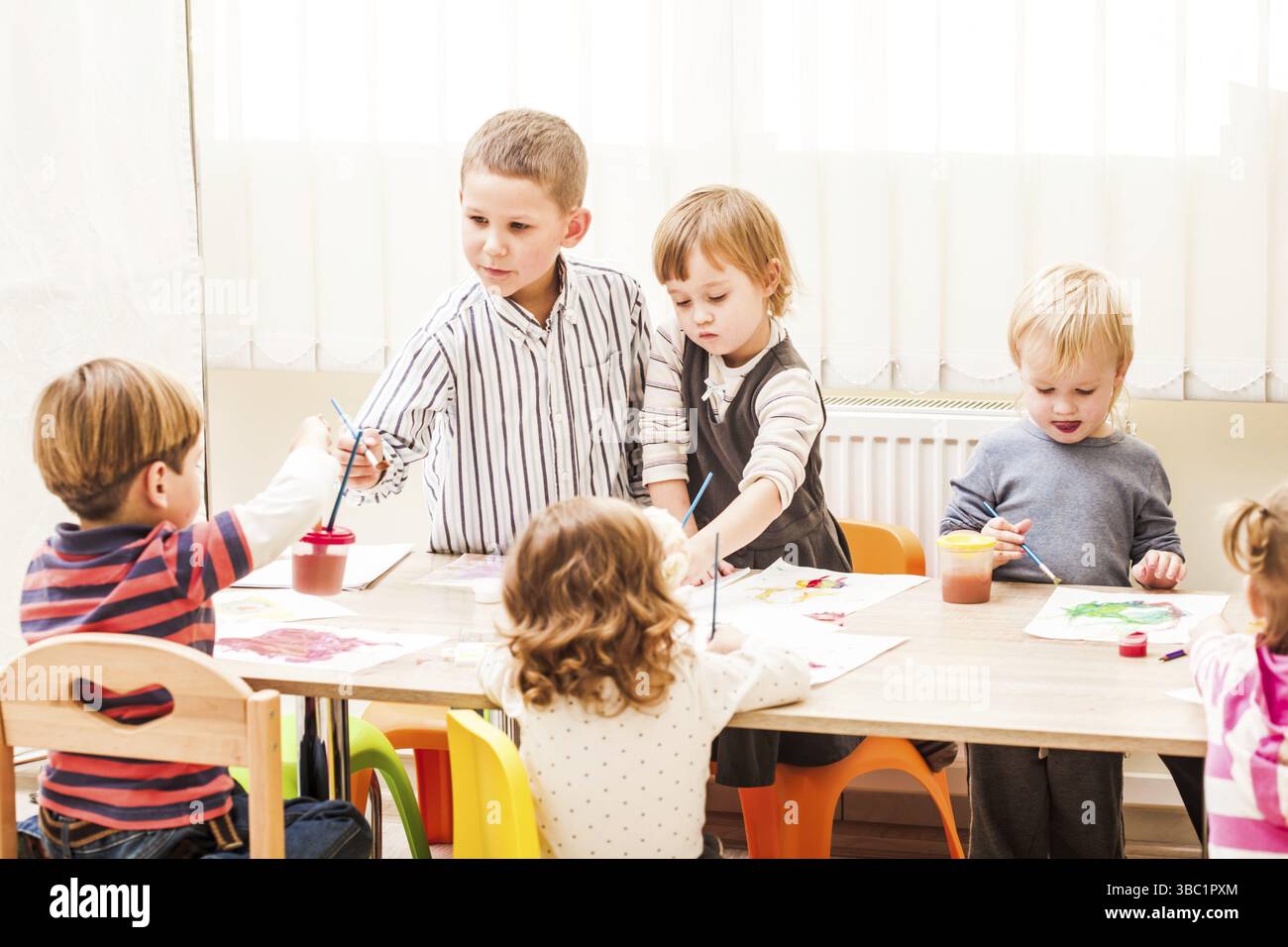 Les enfants apprennent à peindre avec un pinceau et des aquarelles sur papier à la maternelle Banque D'Images