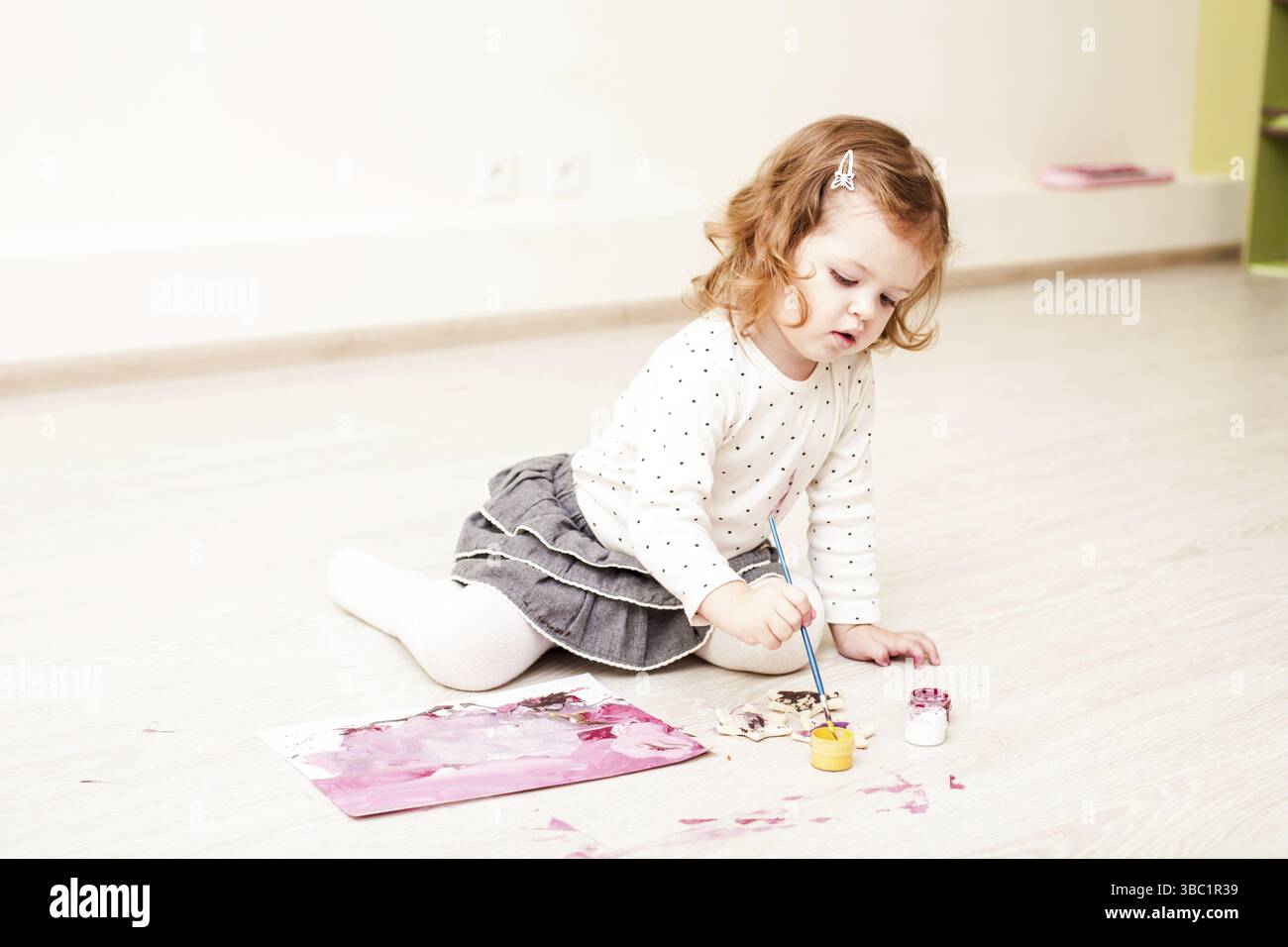 Fille, c'est peindre avec un pinceau et gouache sur papier sur le plancher Banque D'Images