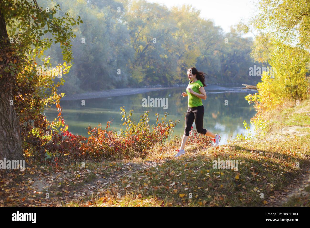 Slimfit Active formation femme à l'automne parc de la ville, près de la rivière. Femme avec bonne hygiène de vie fait son concept de routine en cours à l'automne cit Banque D'Images