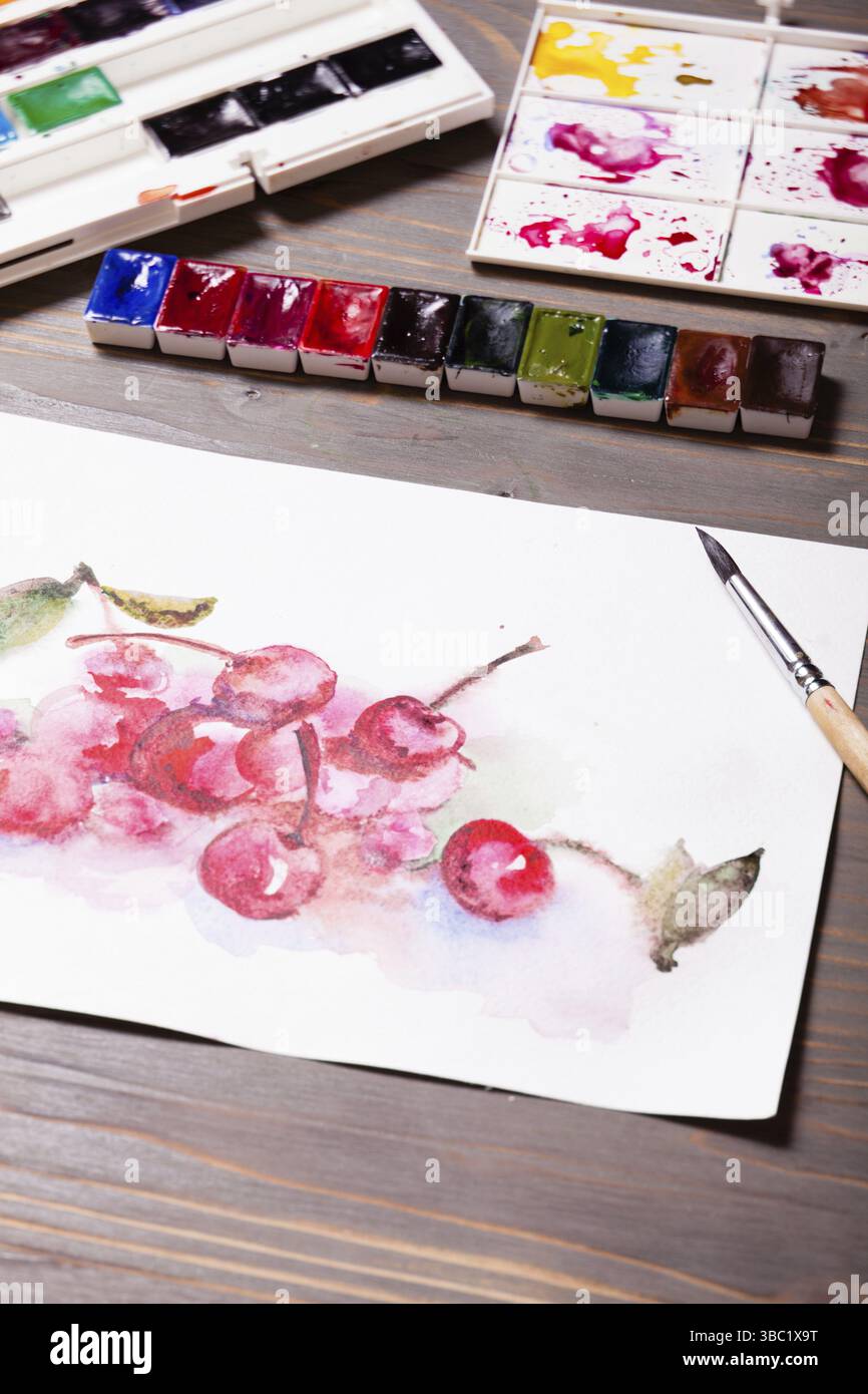 Œuvres d'art, peintures à l'aquarelle cerises avec outils de dessin sur une table en bois Banque D'Images