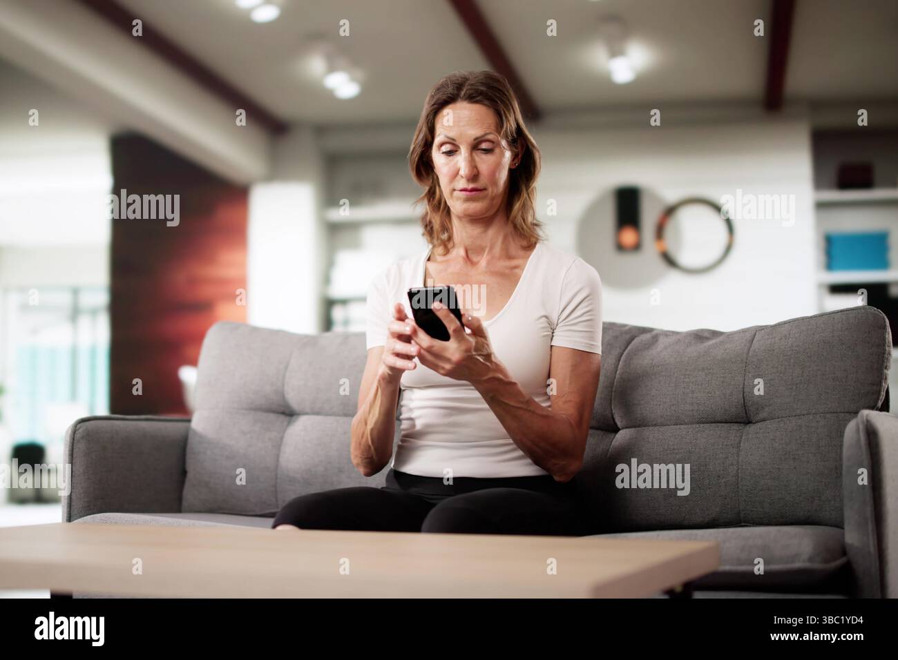 Financial Scam Victim cherche des solutions de paiement sur smartphone à la maison Banque D'Images
