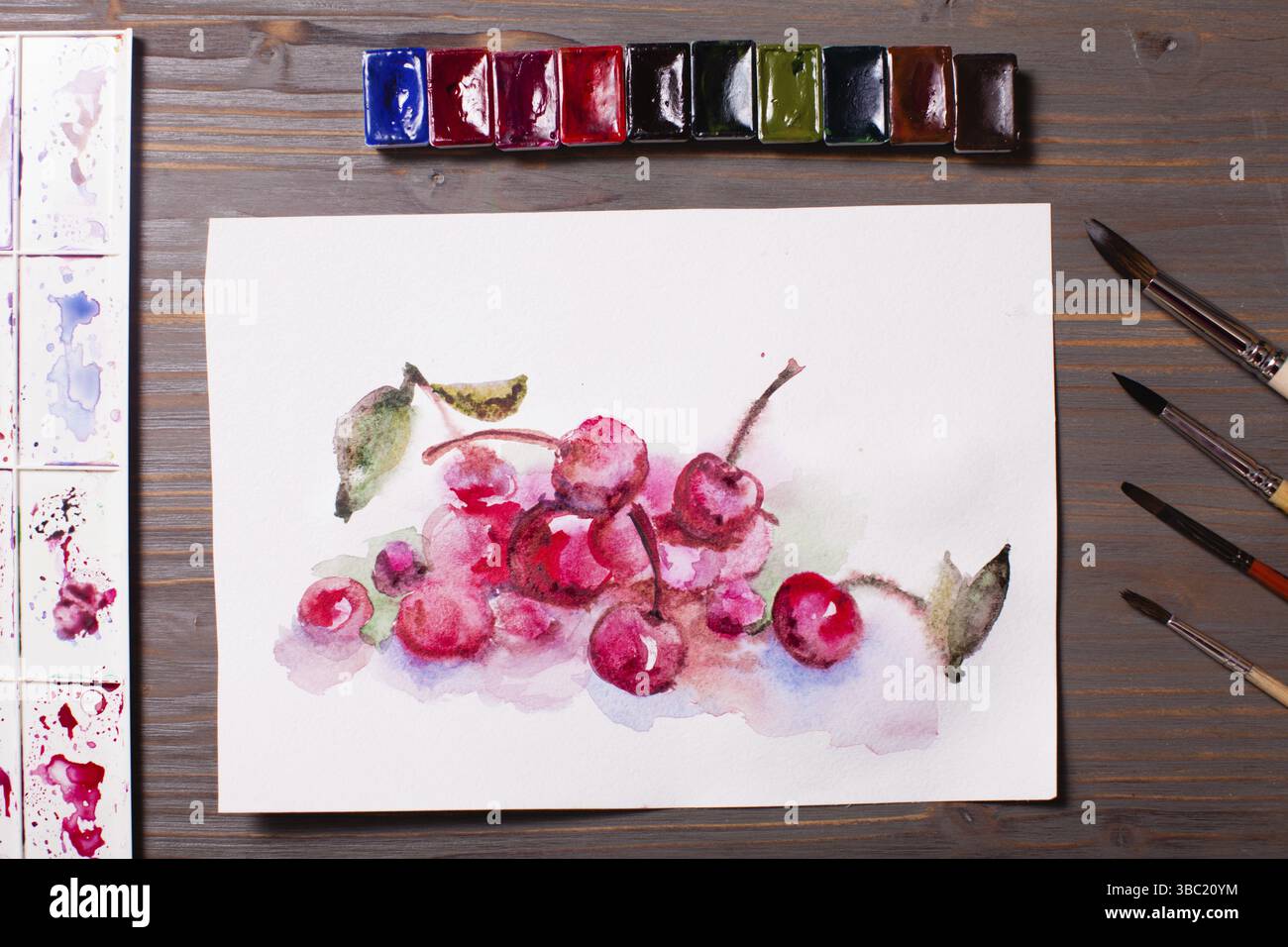 Œuvres d'art, peintures à l'aquarelle cerises avec outils de dessin sur une table en bois Banque D'Images