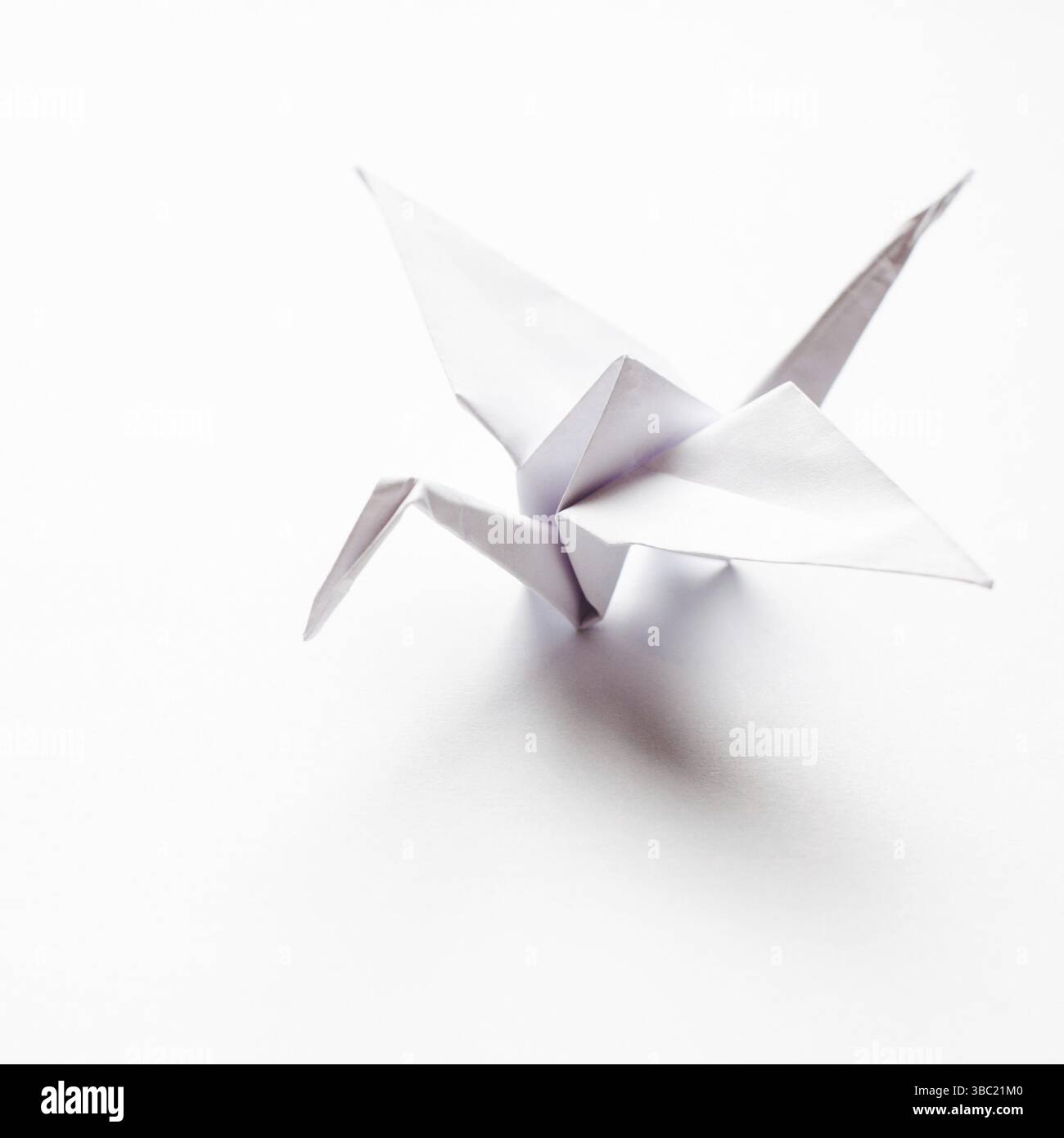 La grue d'origami est en papier blanc, isolée sur fond blanc Banque D'Images