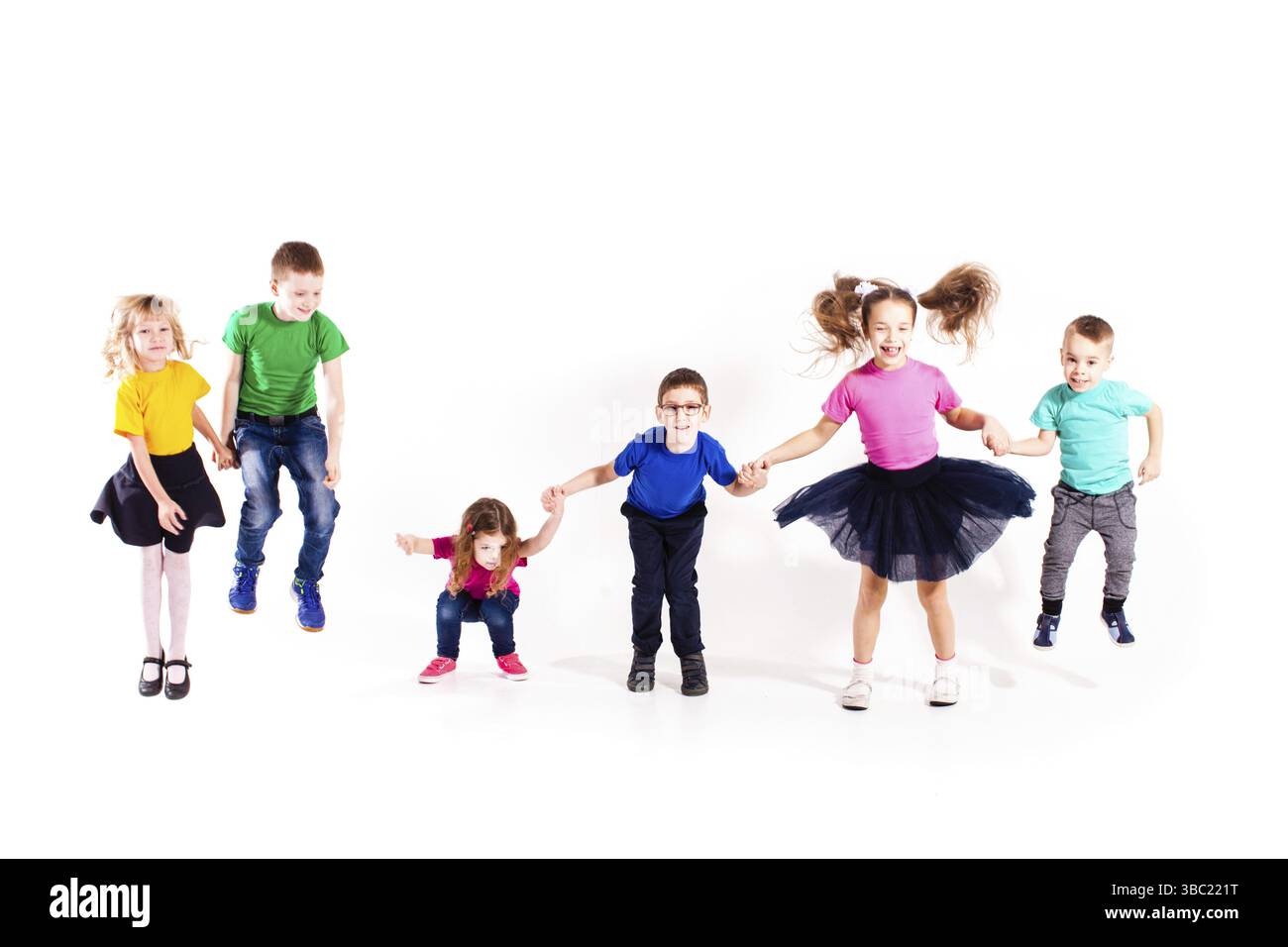 Les garçons et les filles mignons sautent en tenant les mains isolées sur fond blanc Banque D'Images
