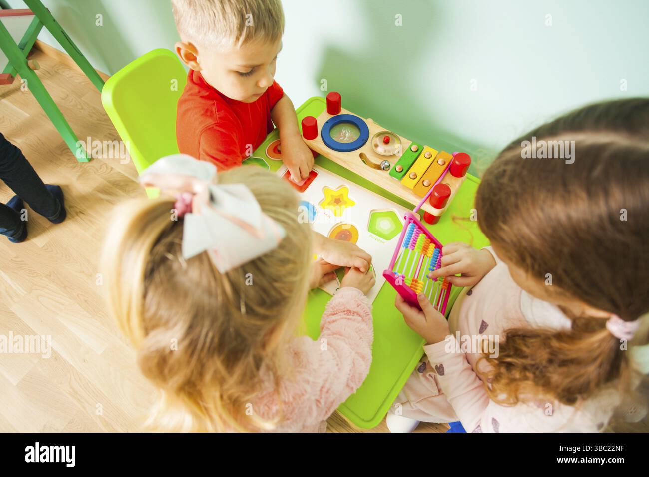 Enfants jouant avec des jouets de musique et de mathématiques. Tout-petits garçons et filles assis à la table dans la salle de jeux. Jouets éducatifs et de développement Banque D'Images