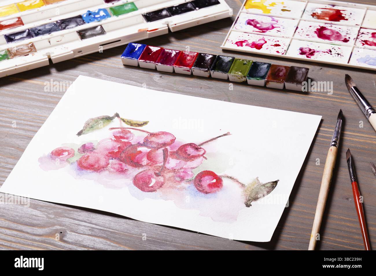 Œuvres d'art, peintures à l'aquarelle cerises avec outils de dessin sur une table en bois Banque D'Images